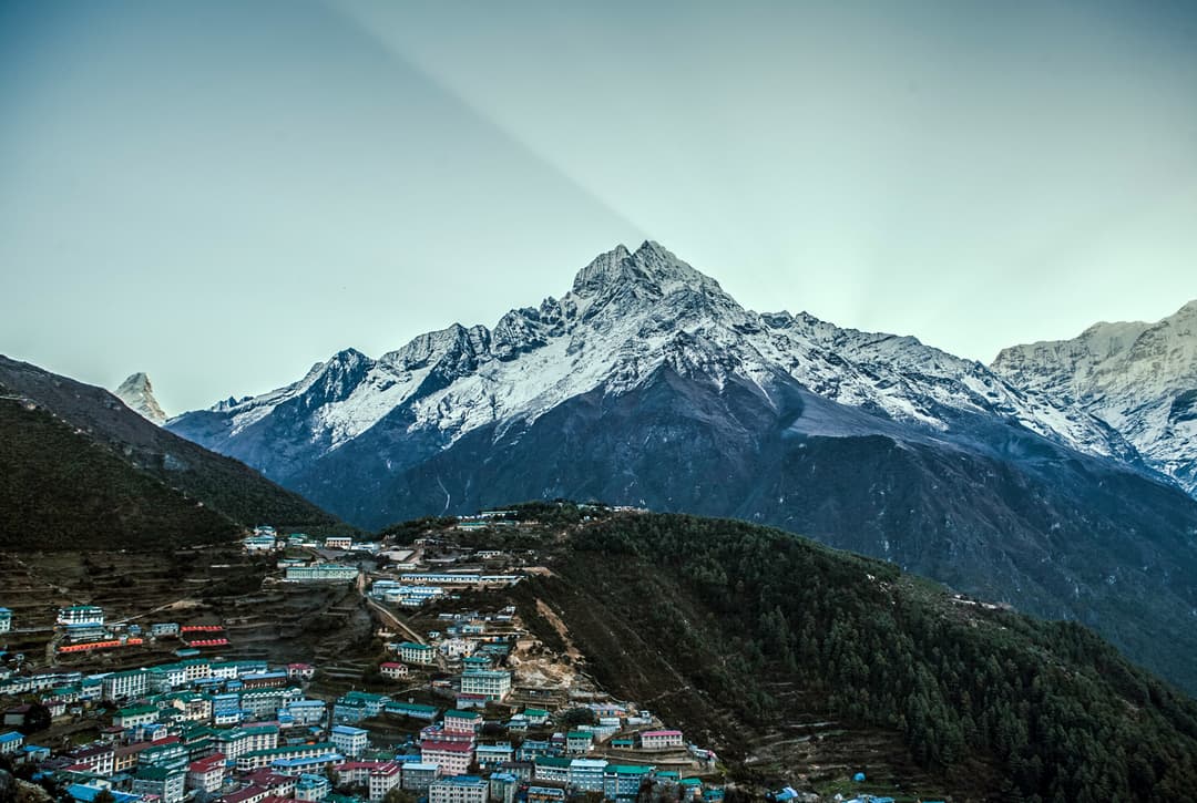 Panoramic View Of Namche Bazaar Village In Nepal Nestled In A Valley Beneath A Snow Capped Peak