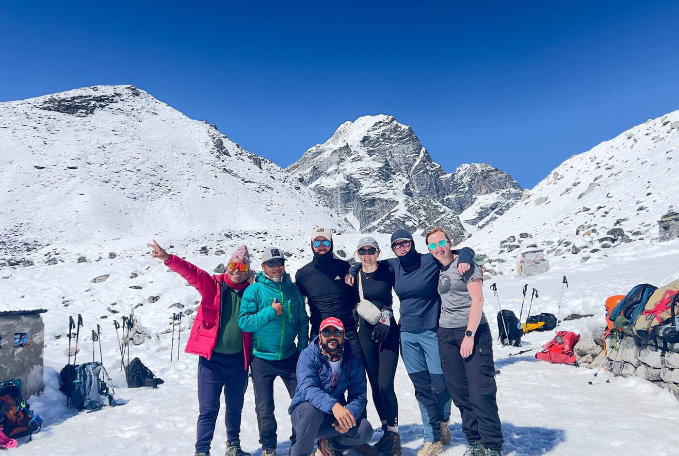 Trekkers standing at Thukla Pass memorials on the Everest Base Camp trek above Dhugla, surrounded by high-altitude terrain.