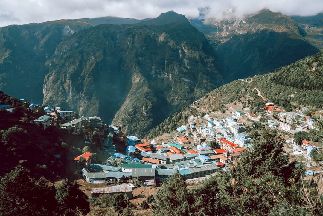 Aerial View Of Namche Bazaar Town Nestled In A Mountain Valley Surrounded By Forested Ridges