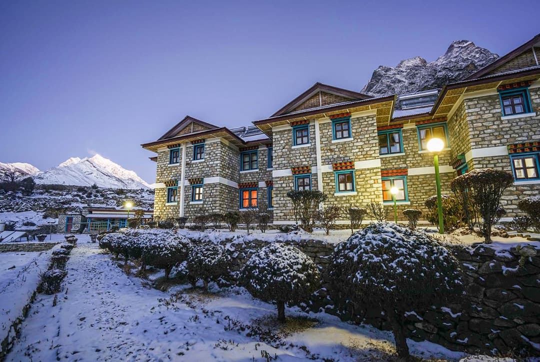Everest Summit Lodge At Mende Glowing Warmly At Dusk With Snow Covered Grounds And Mountain Peaks