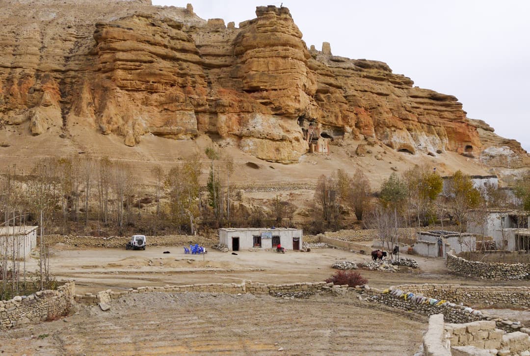 Chhoser Village With Ancient Sky Caves Carved Into Towering Sandstone Cliffs Near Lo Manthang